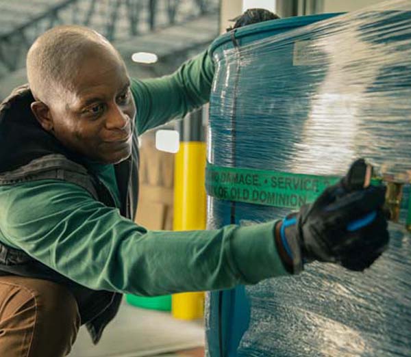 Dock worker securing freight on a pallet with ratchet straps 